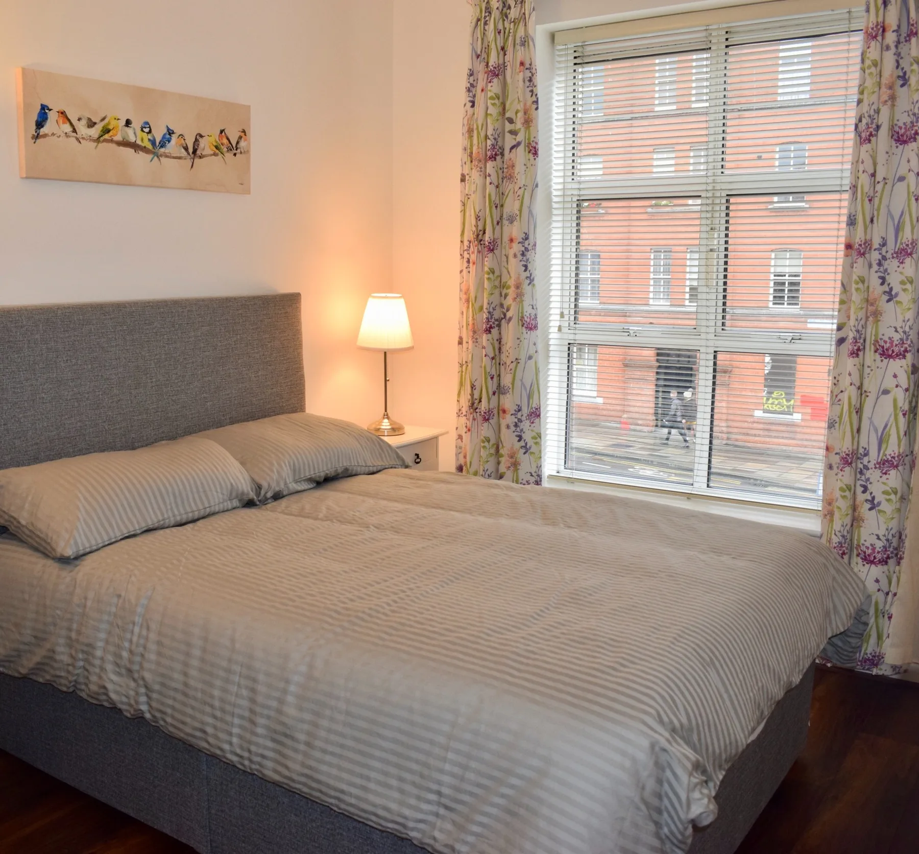 Un dormitorio con una cama bien tendida junto a una ventana.