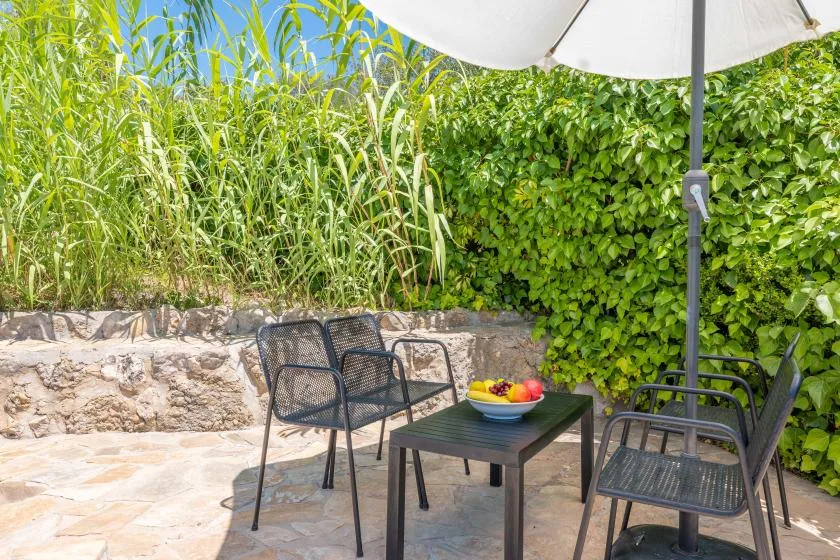 An outdoor patio with a table and seating beneath a large umbrella.
