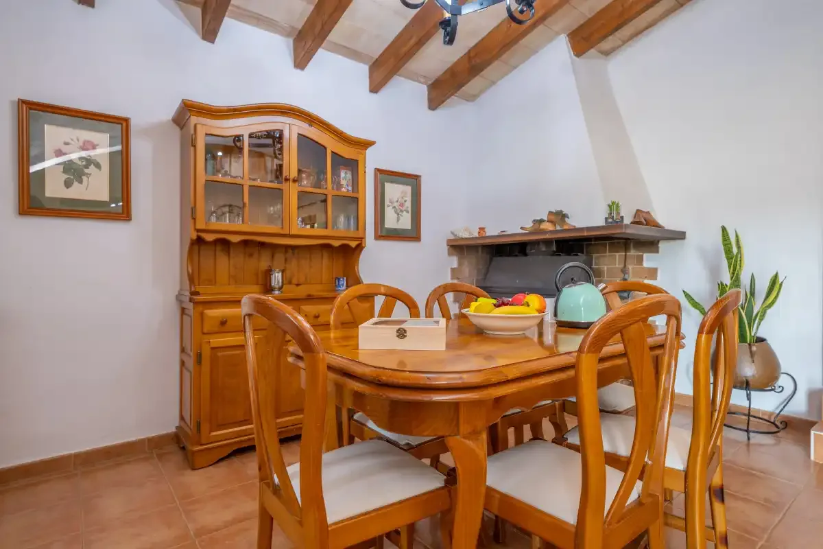A dining room with a wooden table and chairs beneath exposed ceiling beams.