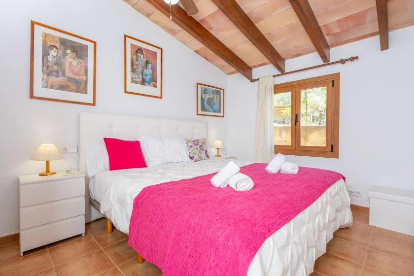 A bedroom with a bed dressed in white and bright pink bedding.