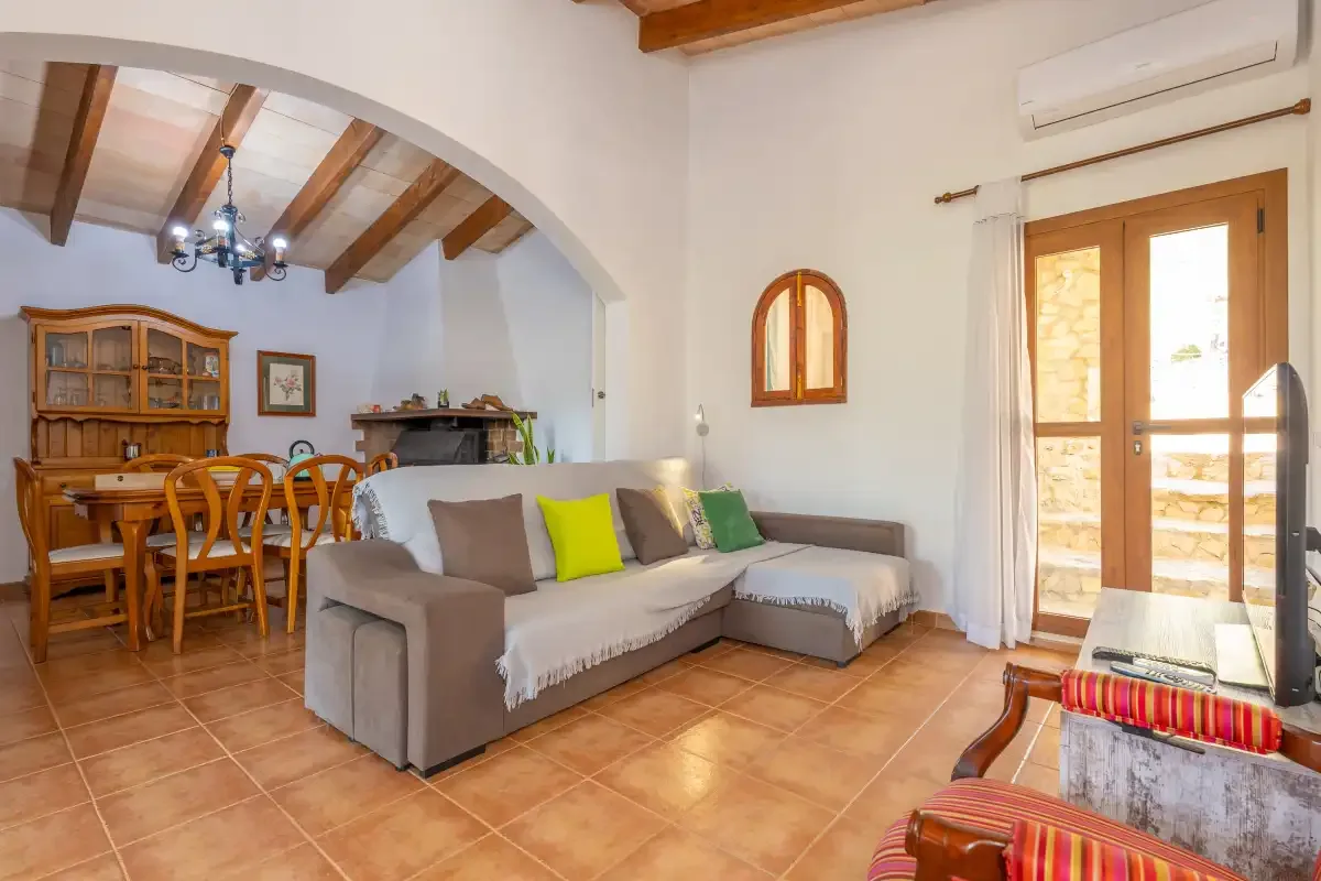 A living room with a dining area, timber ceiling beams, and a glass door.