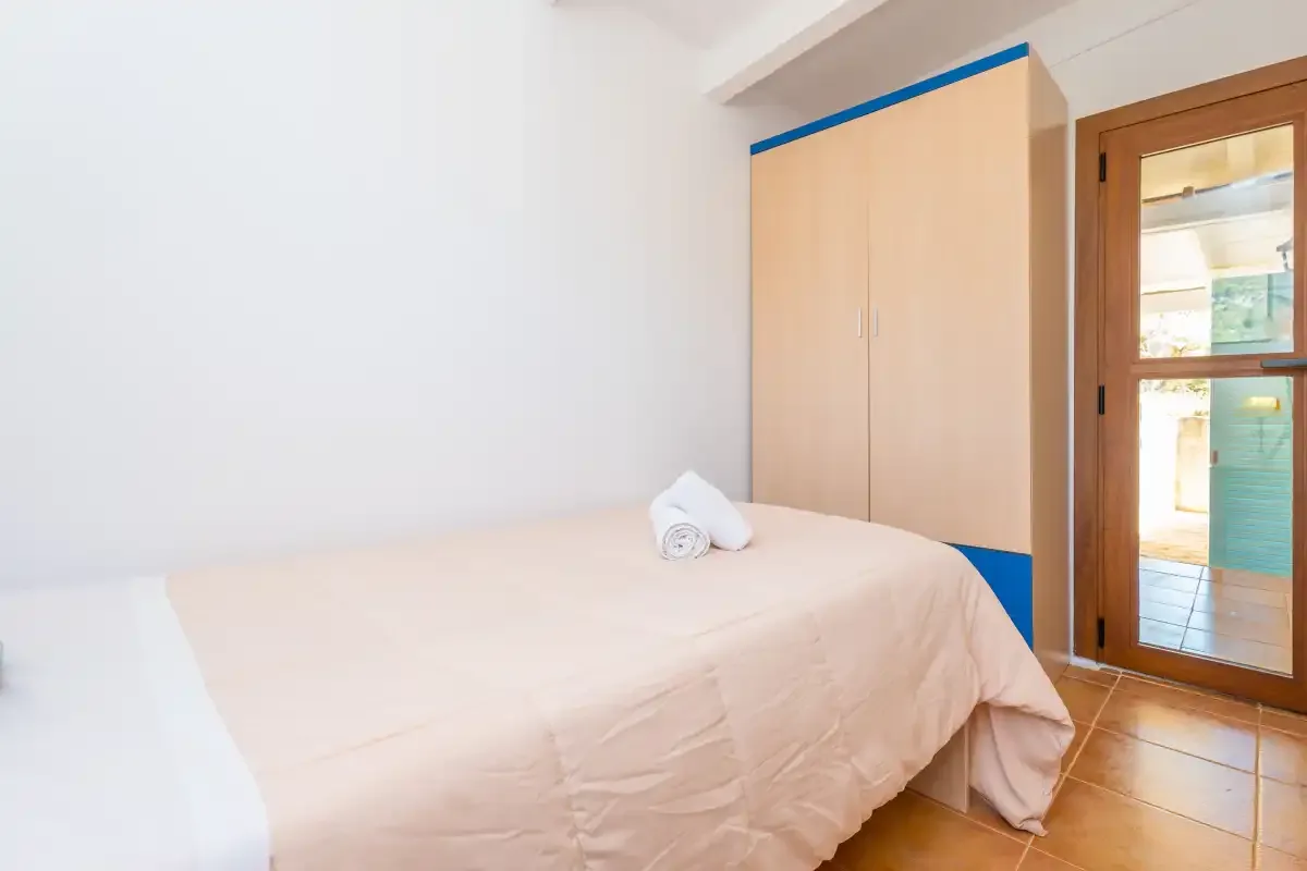 A bedroom with a bed beside a wardrobe and a glass door.