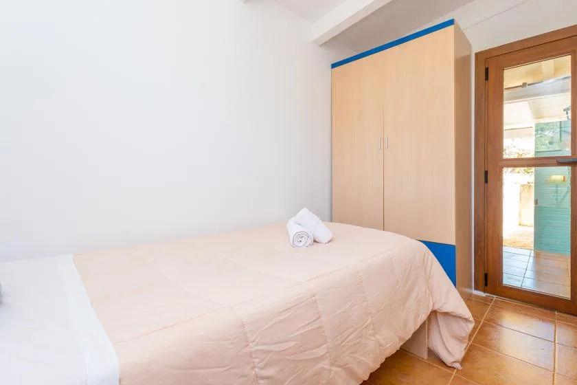 A bedroom with a bed beside a built-in wardrobe and glass door.