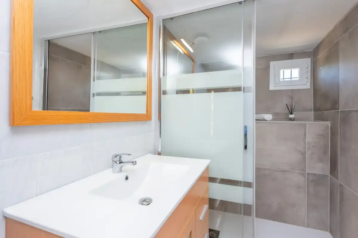 A bathroom with a sink, mirror, and glass shower.