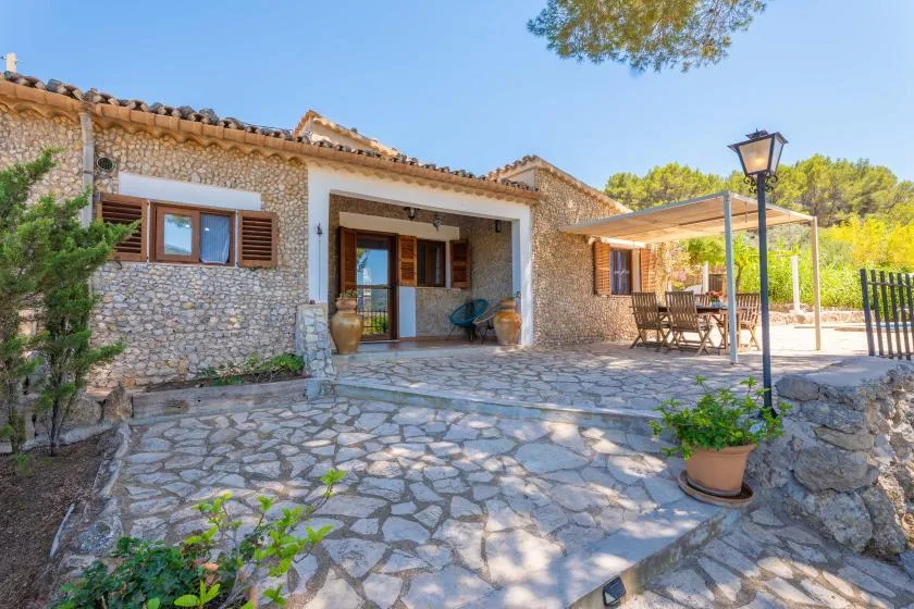 A stone house opens onto a paved patio with outdoor seating.