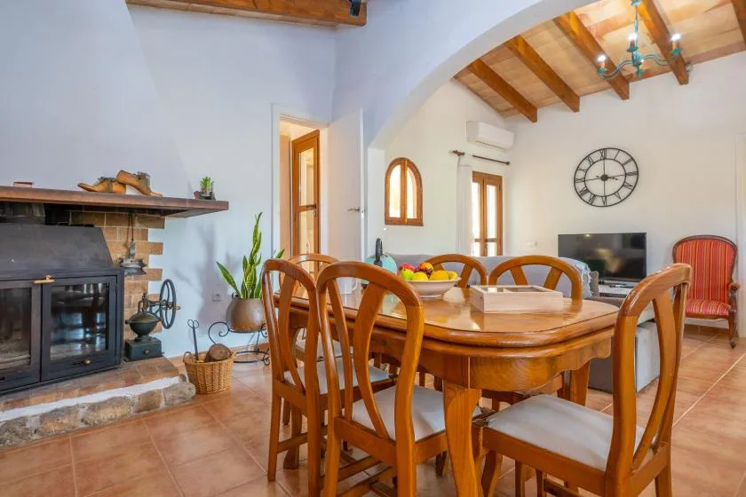 A dining area with a wooden table and chairs beside a fireplace.