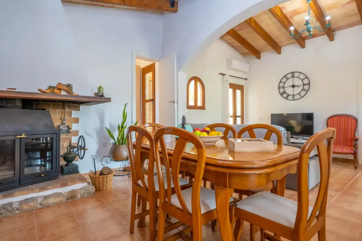 A dining room with a wooden table and chairs beside a fireplace.
