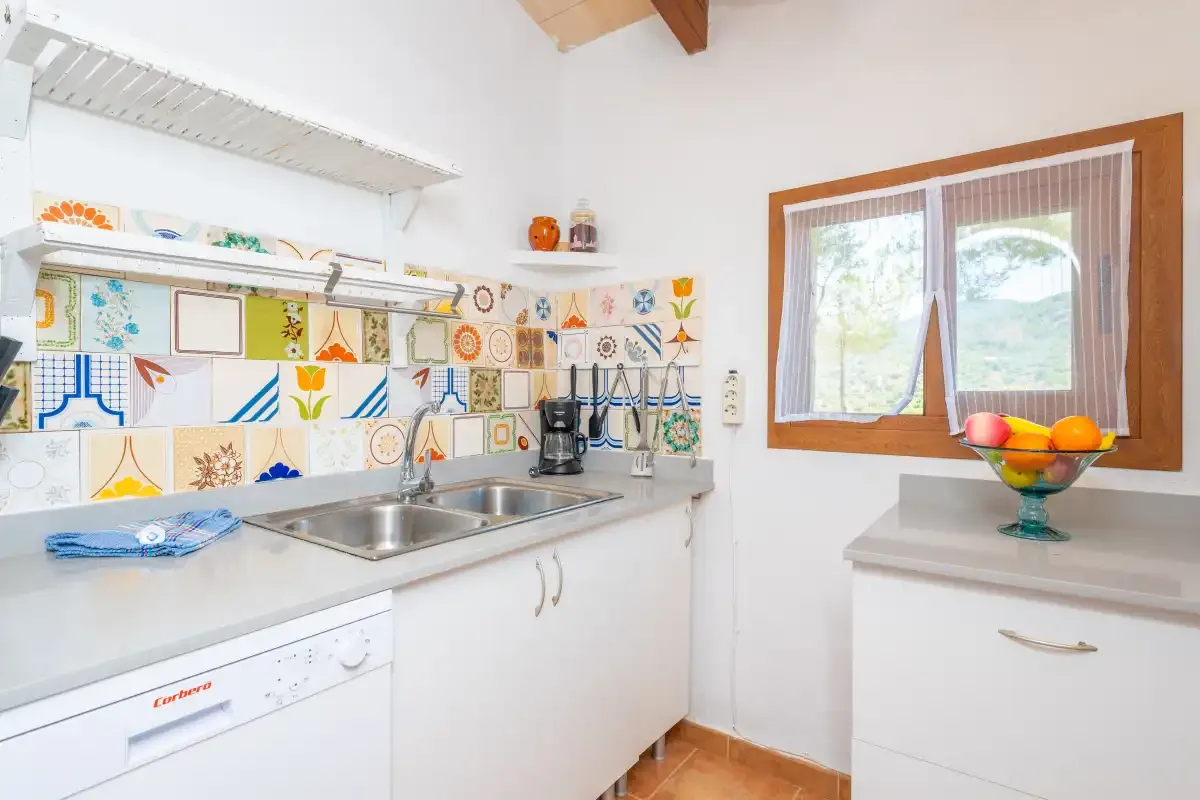 A bright kitchen with a sink, countertop, and colorful patterned backsplash.