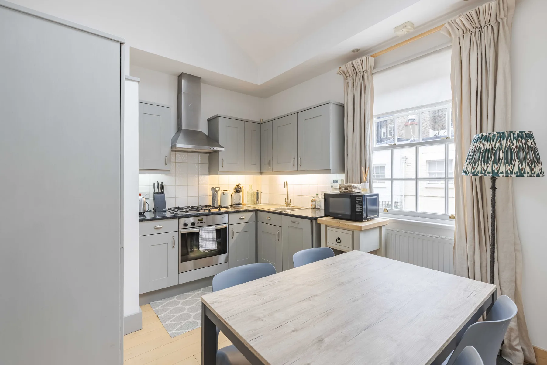 A bright kitchen and dining area with gray cabinets and a table by the window.