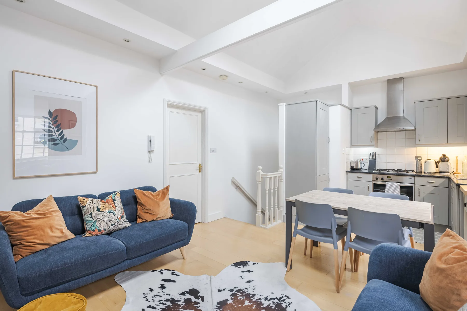 A bright open-plan living and dining area with a blue sofa and kitchen.