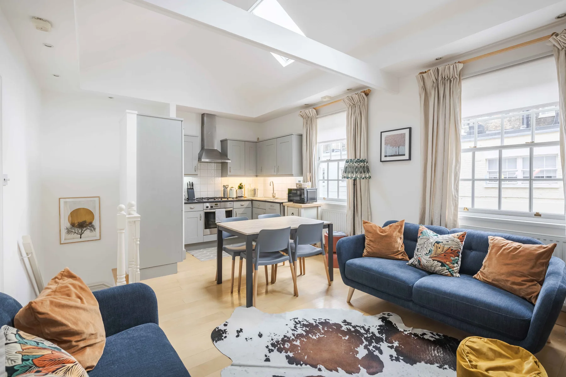 A bright living room with a dining table and an open kitchen.