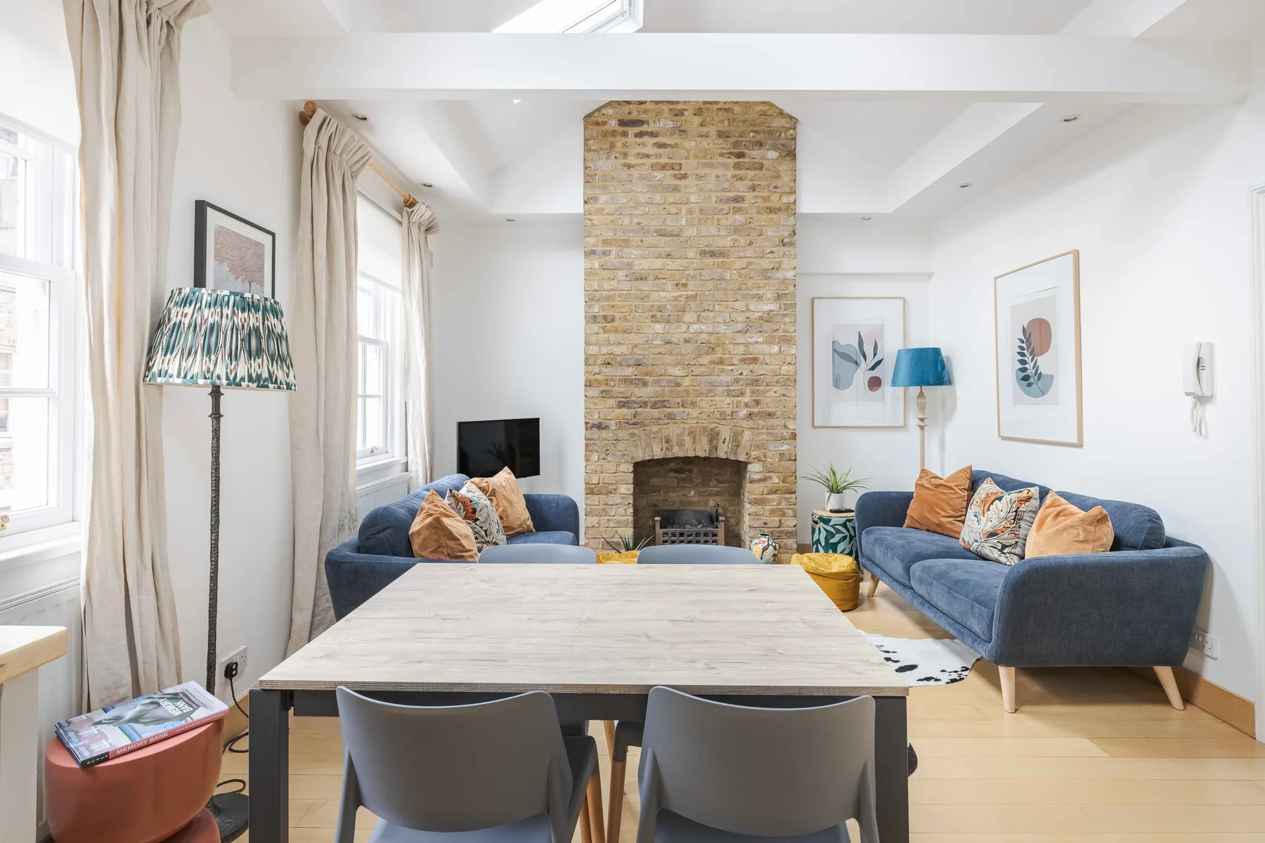 A bright living and dining room with blue seating around a large table.