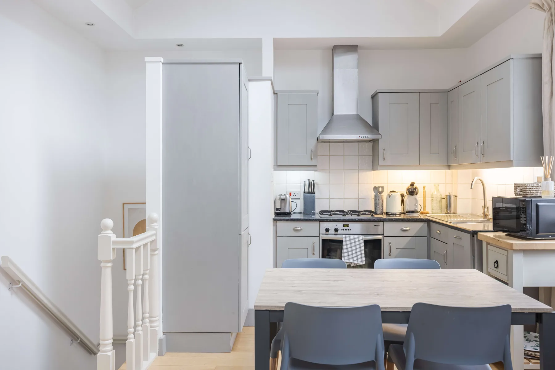 A bright kitchen with gray cabinets and a dining table in the foreground.