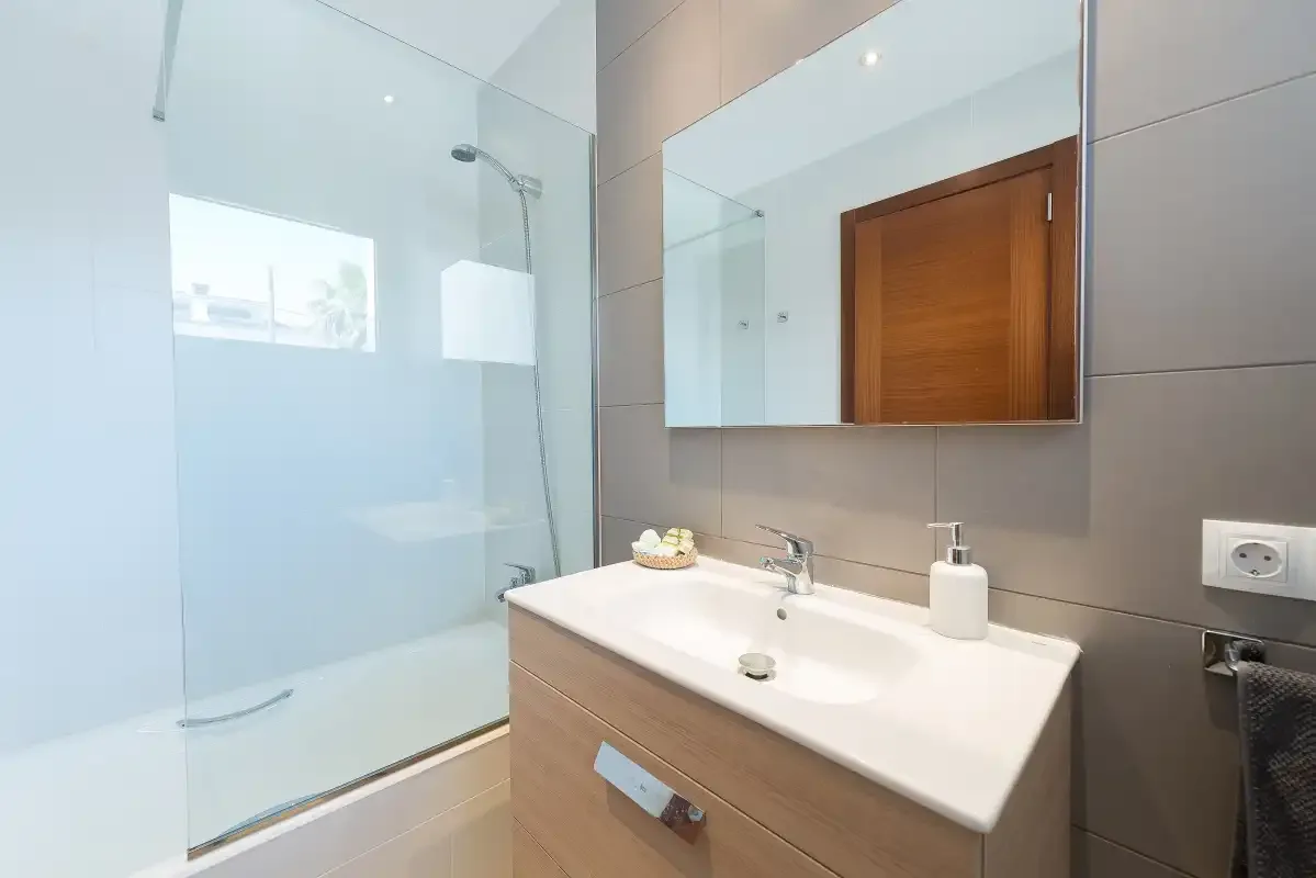 A modern bathroom with a sink, mirror, and glass shower.