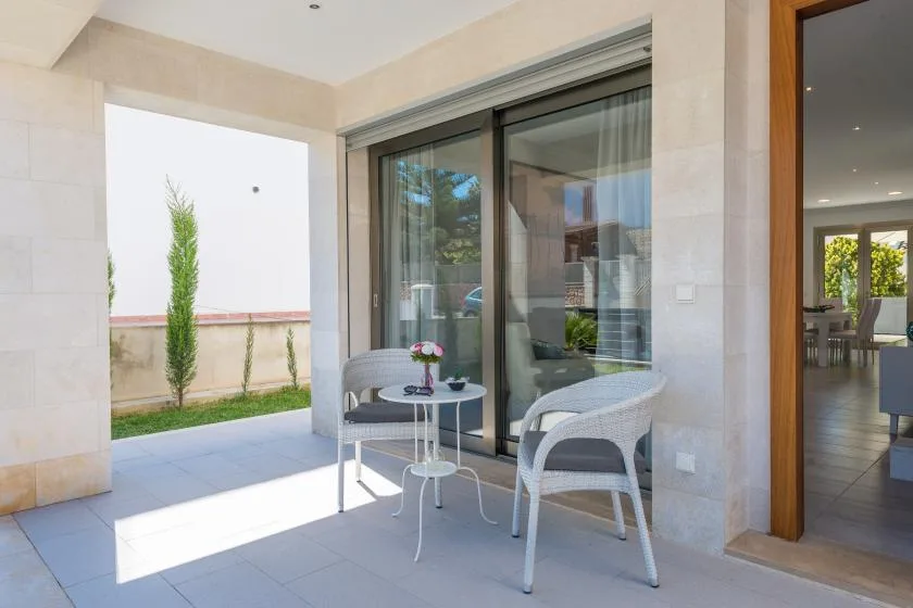 A covered patio with seating beside large sliding glass doors.