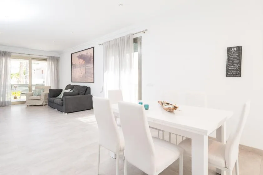 A bright living and dining area with a white table and gray seating.