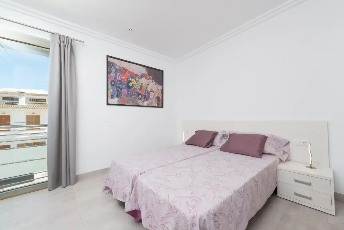 A bedroom with a double bed beside a glass balcony door.