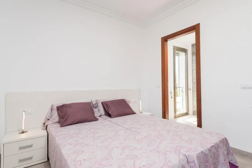 A bedroom with a bed covered in pale patterned bedding.