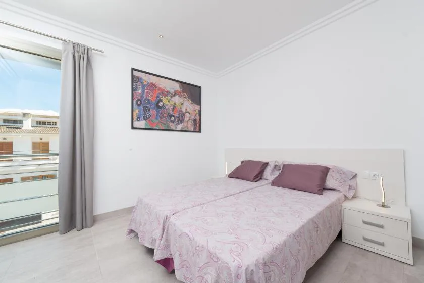 A bedroom with a bed beside a curtained window.