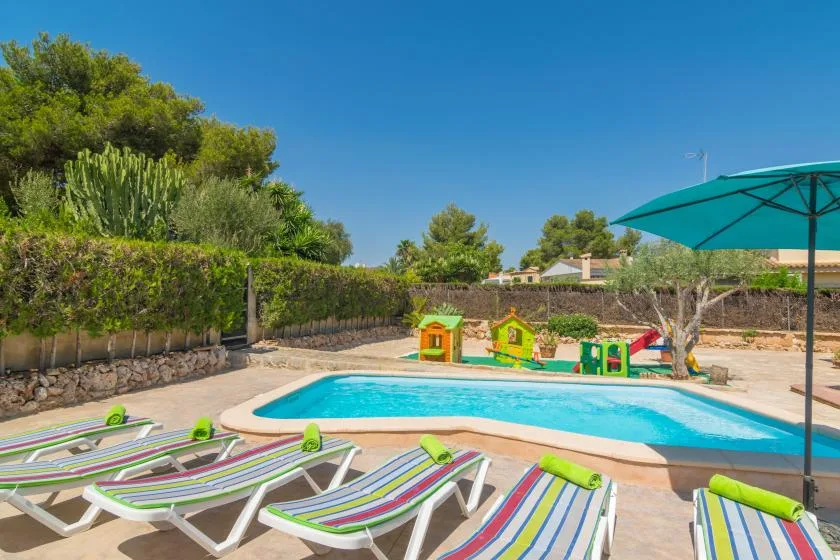 Outdoor pool area with striped loungers and a large shade umbrella.