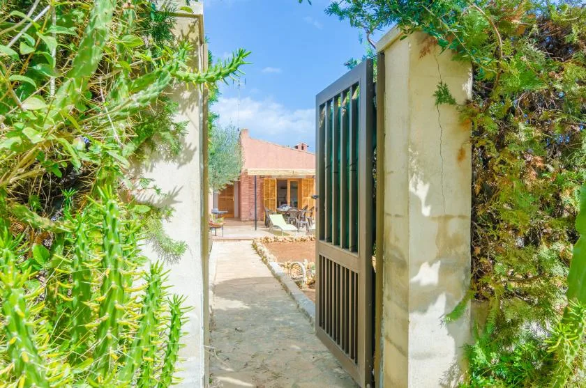 An open garden gate leads along a stone path toward a house.