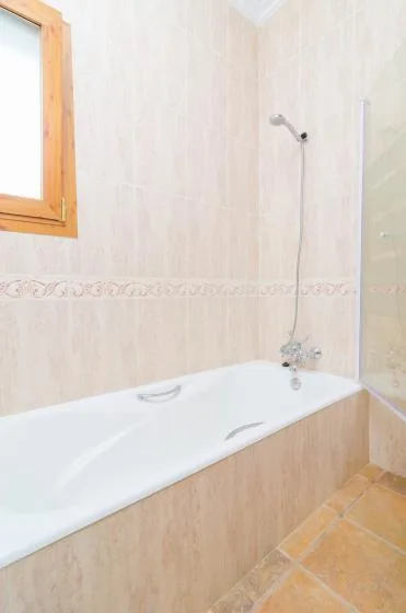 A tiled bathroom with a bathtub and wall-mounted shower.