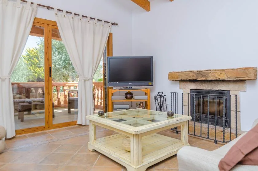 A living room with a glass-topped coffee table, television, and fireplace.