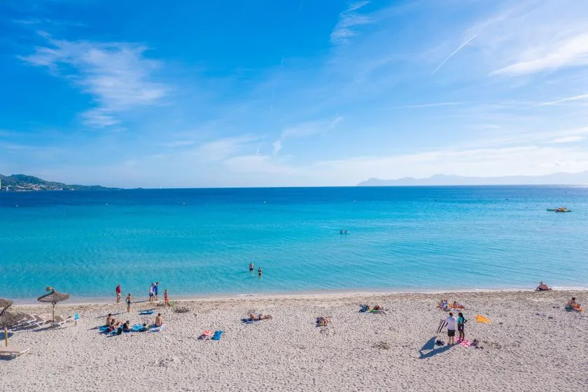 Una playa de guijarros se une a aguas turquesas tranquilas bajo un cielo azul.