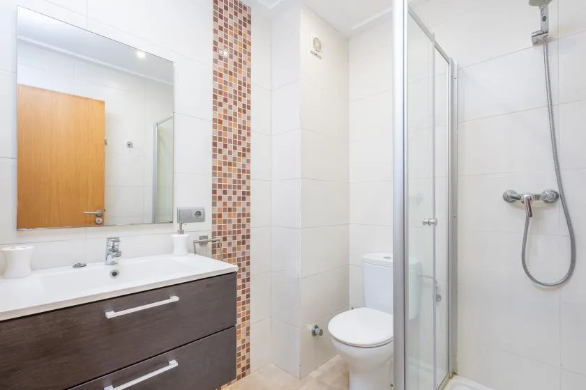 Un baño luminoso con lavabo, inodoro y ducha de cristal.