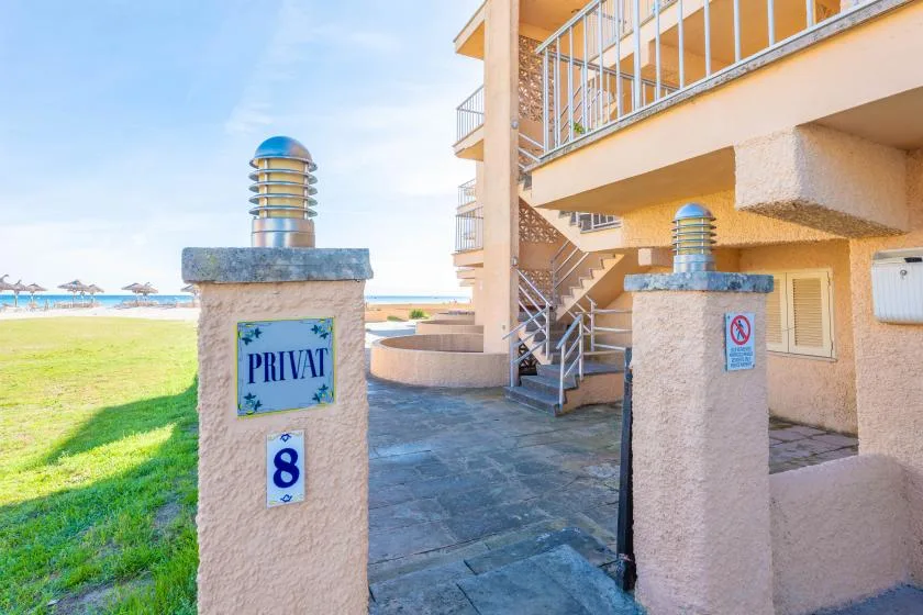 Una entrada residencial junto al mar, con pilares de piedra junto a la playa.
