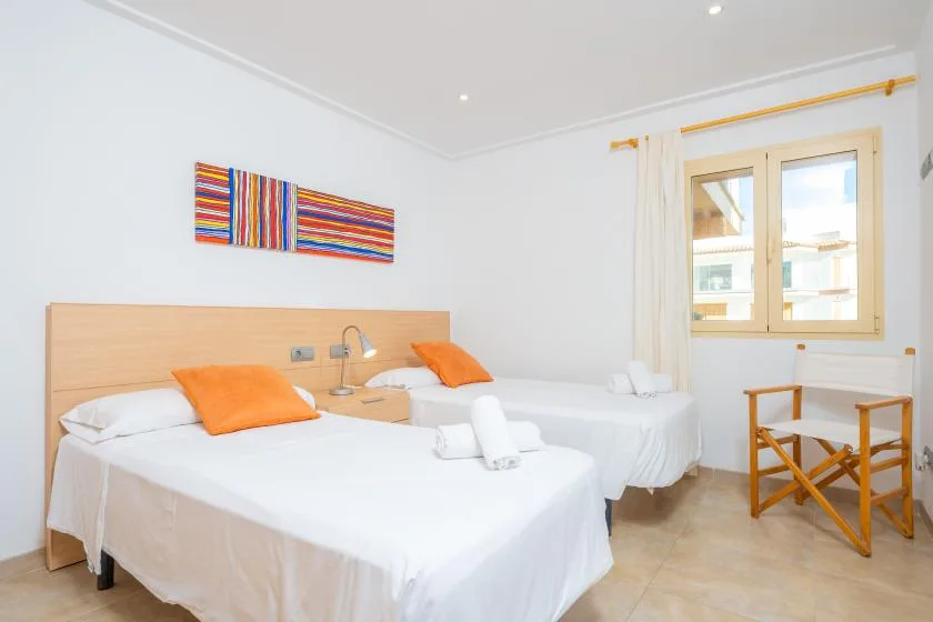 Un dormitorio luminoso con dos camas y arte colorido en la pared.