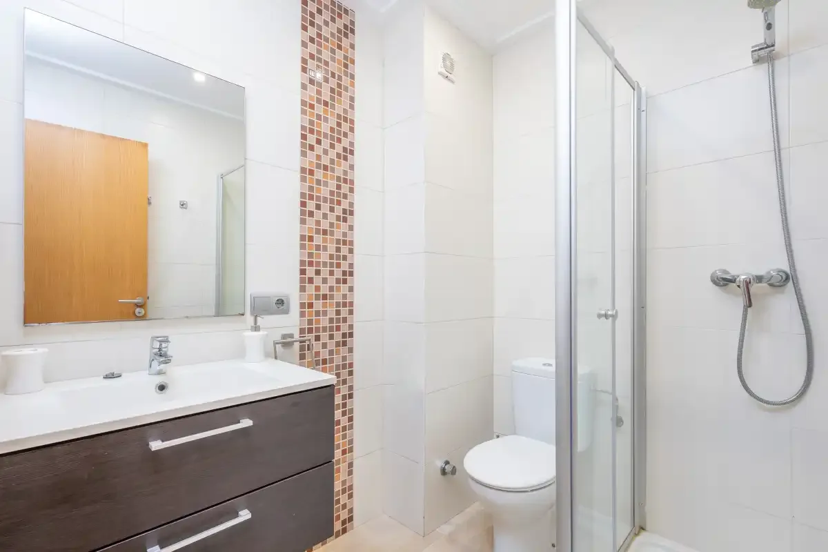 Baño con lavabo, inodoro y ducha de cristal.