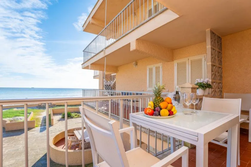Una zona de comedor en el balcón da al mar, con mesa y sillas.