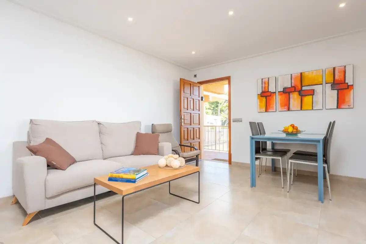 Una luminosa sala de estar y comedor cuenta con un sofá, una mesa de centro y un conjunto de comedor.