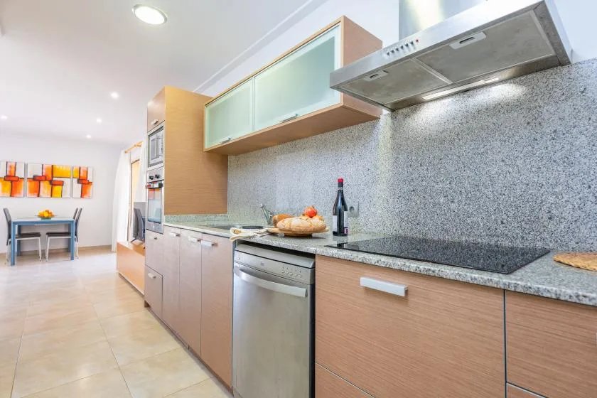 Una cocina moderna con gabinetes de madera, encimera y electrodomésticos de acero inoxidable.