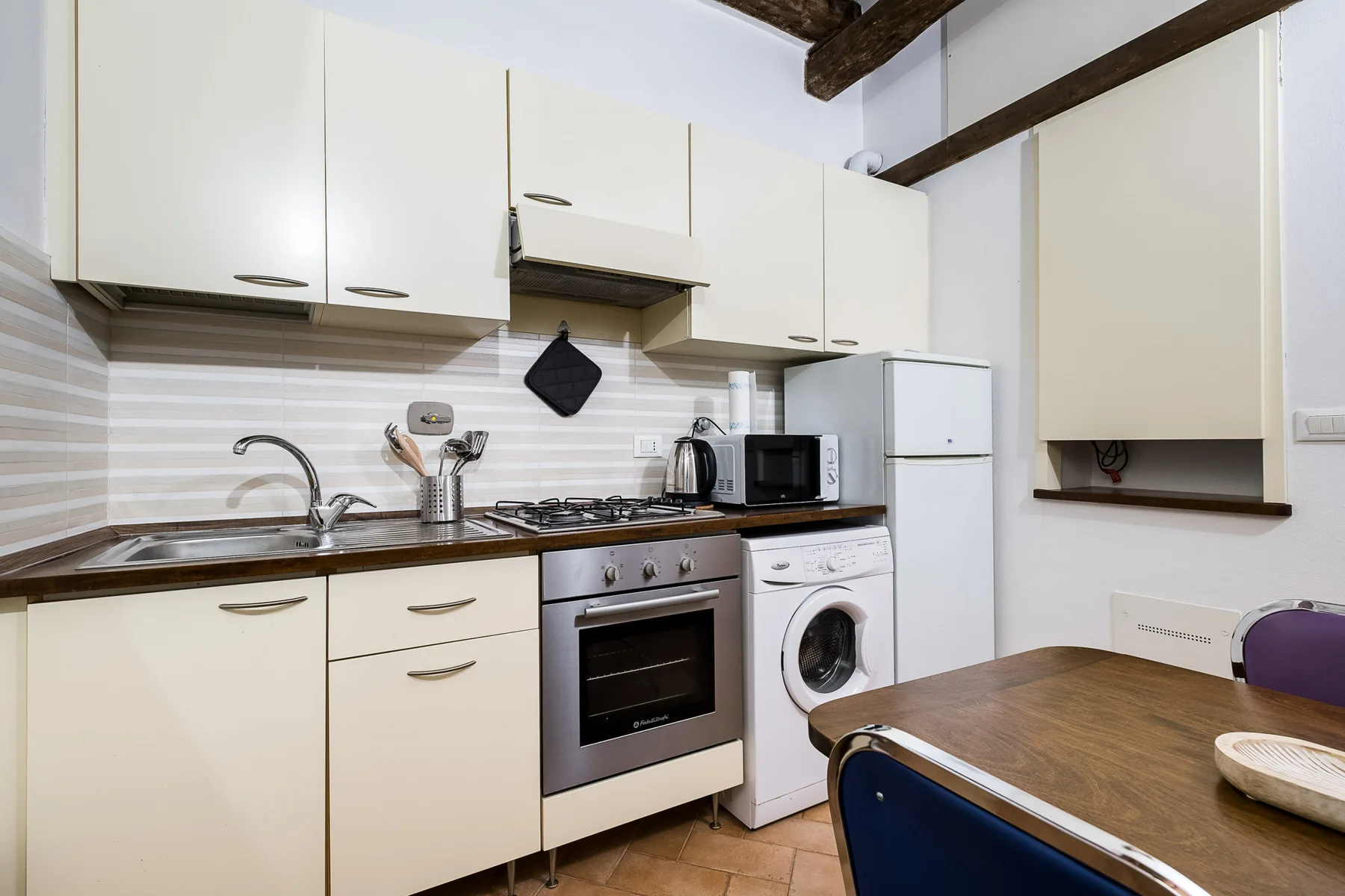 A compact kitchen with white cabinets, a countertop, and a dining table.