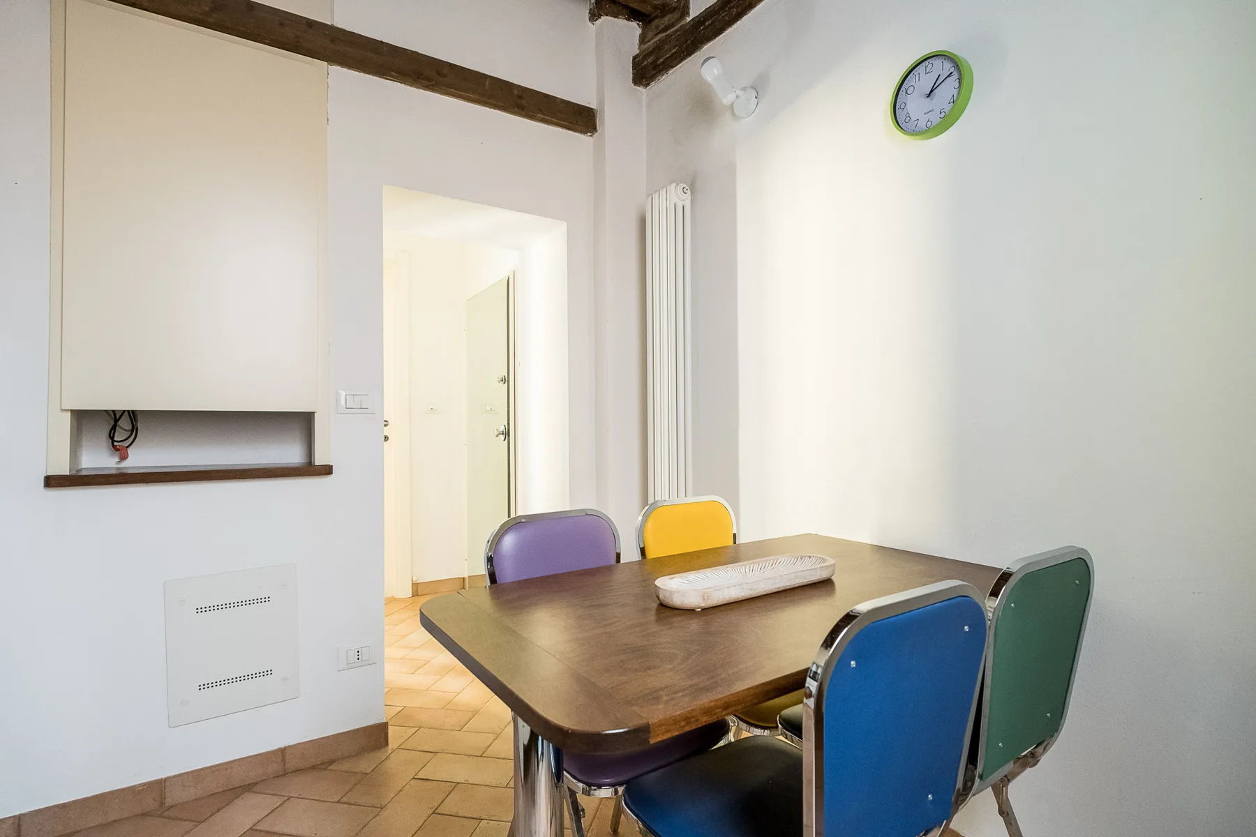 A dining area with a wooden table and colorful chairs.