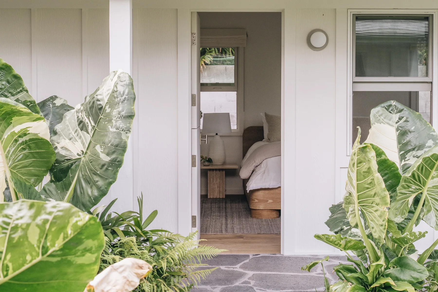 An open doorway reveals a bedroom with a bed and a small desk.