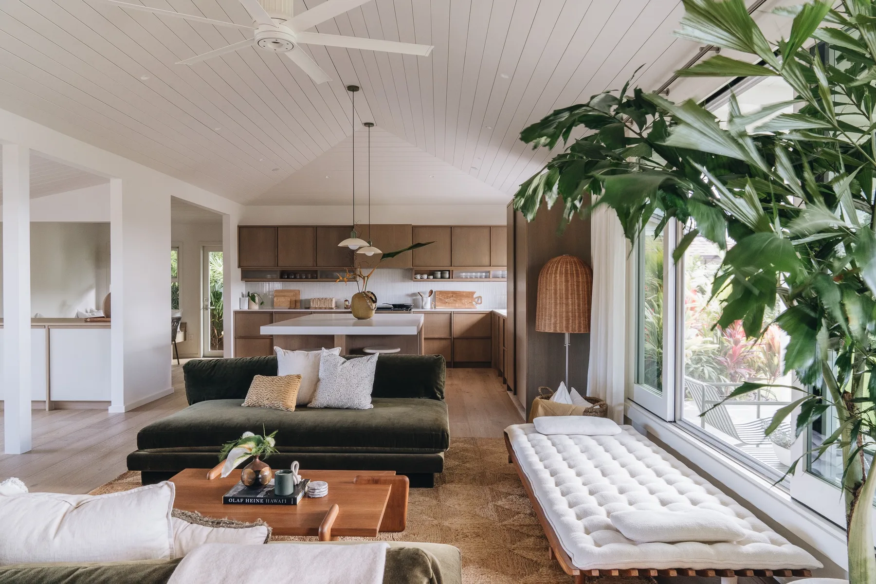 A bright living room with a dark sofa, a low table, and large windows.