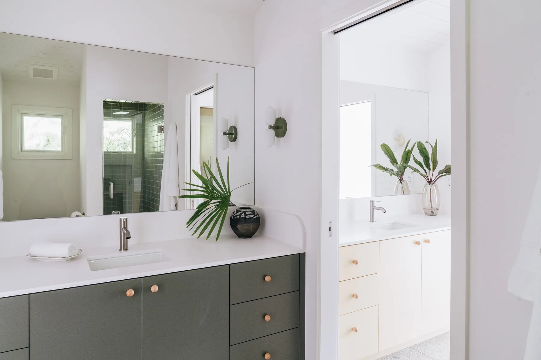 A bright bathroom vanity with a wide mirror and a potted plant.