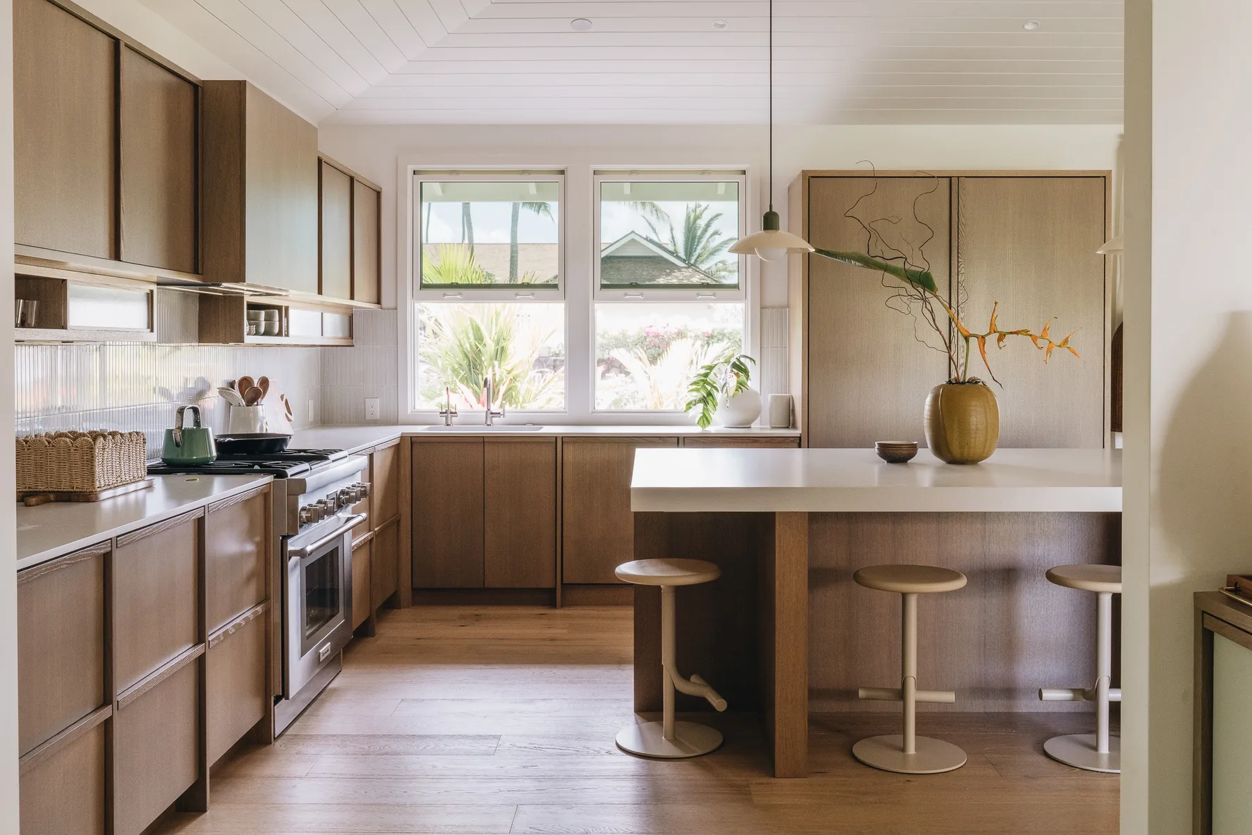 A bright kitchen with wooden cabinets, a central island, and windows above the sink.