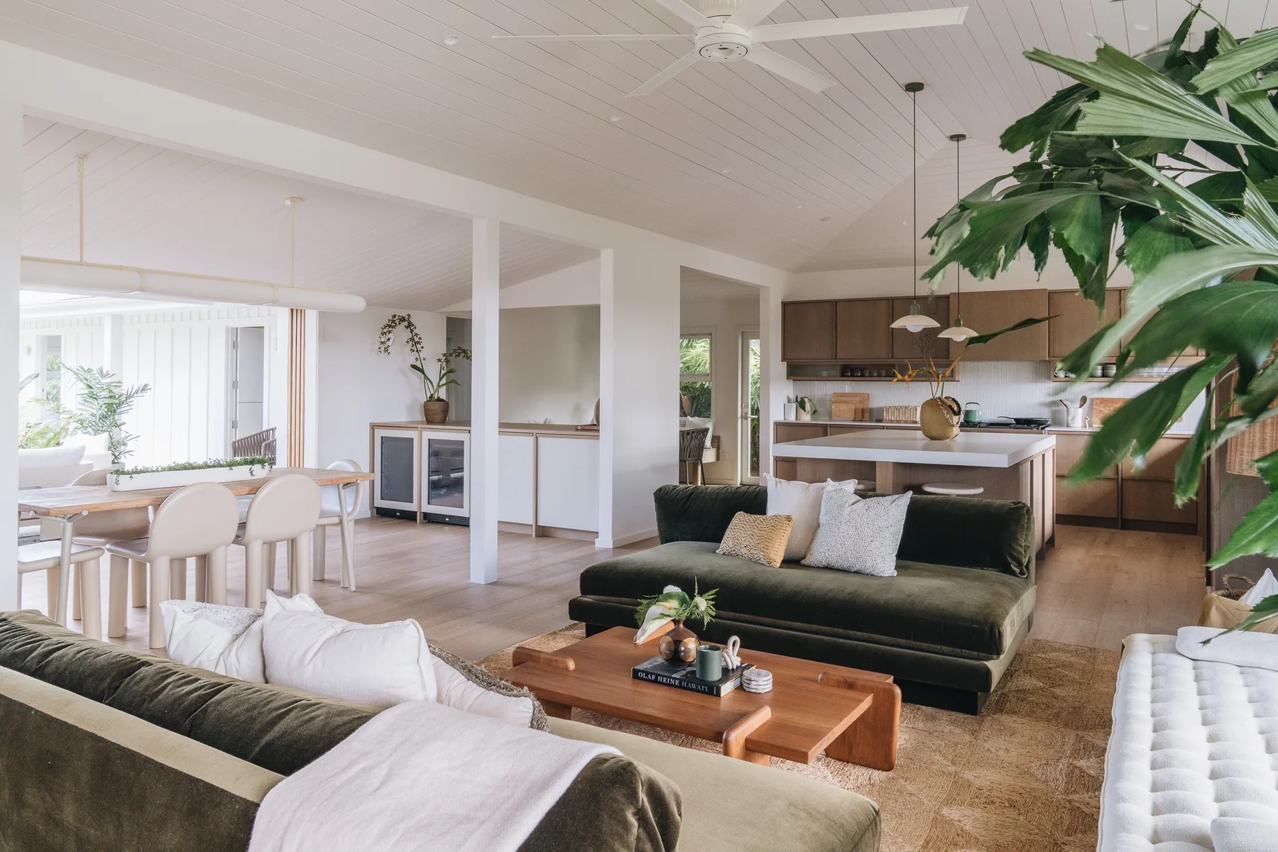 A bright open-plan living and dining area has a dark sofa and a dining table.