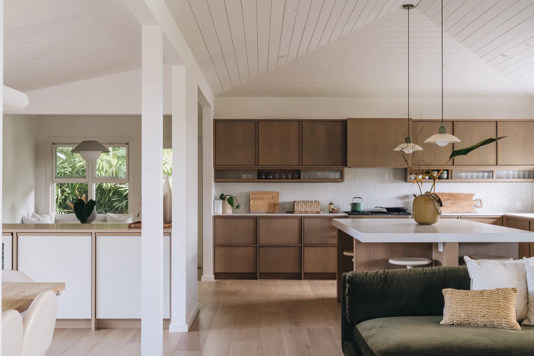 A bright kitchen and living area with dark cabinetry and a central island.