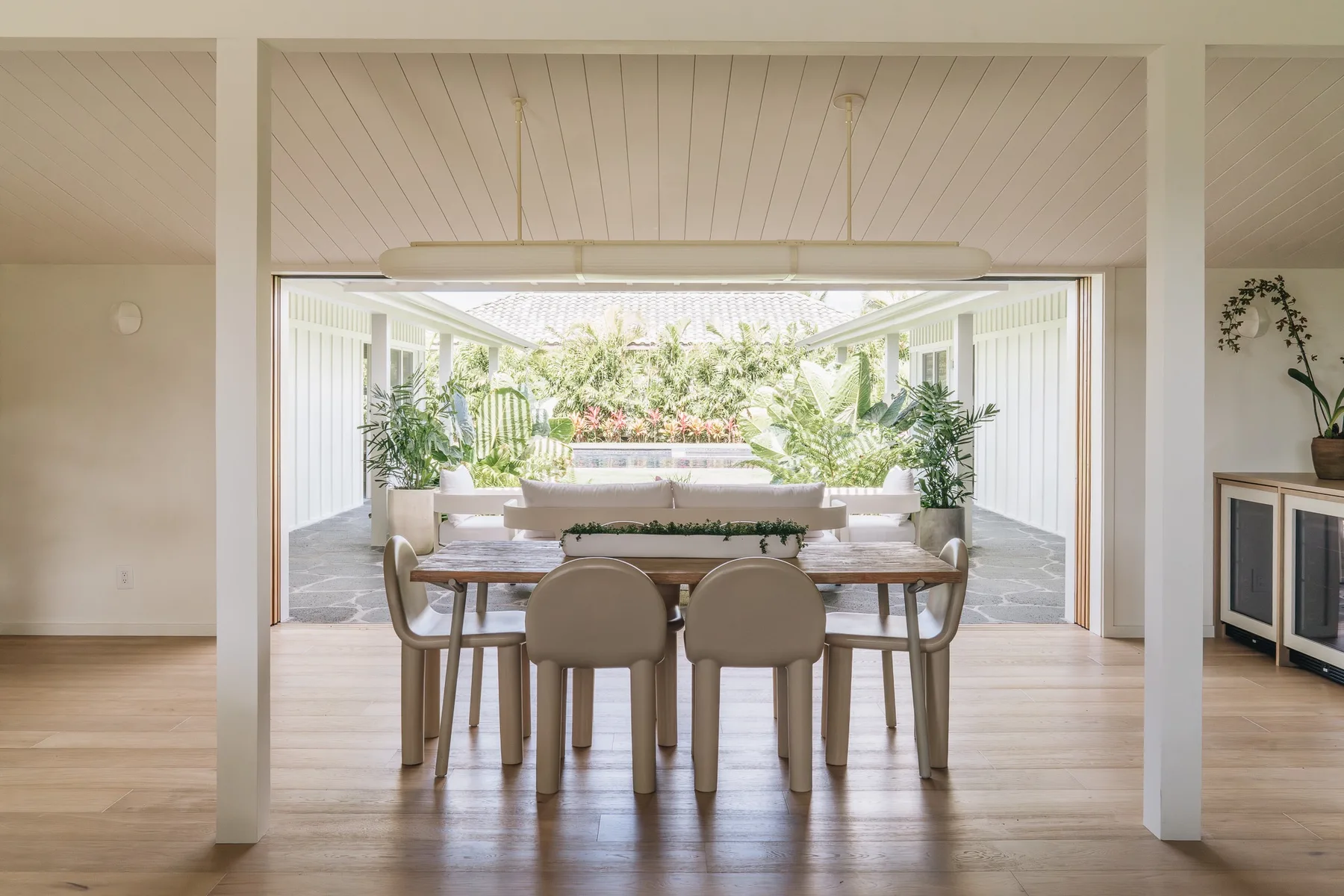 A dining area opens onto a bright patio filled with greenery.