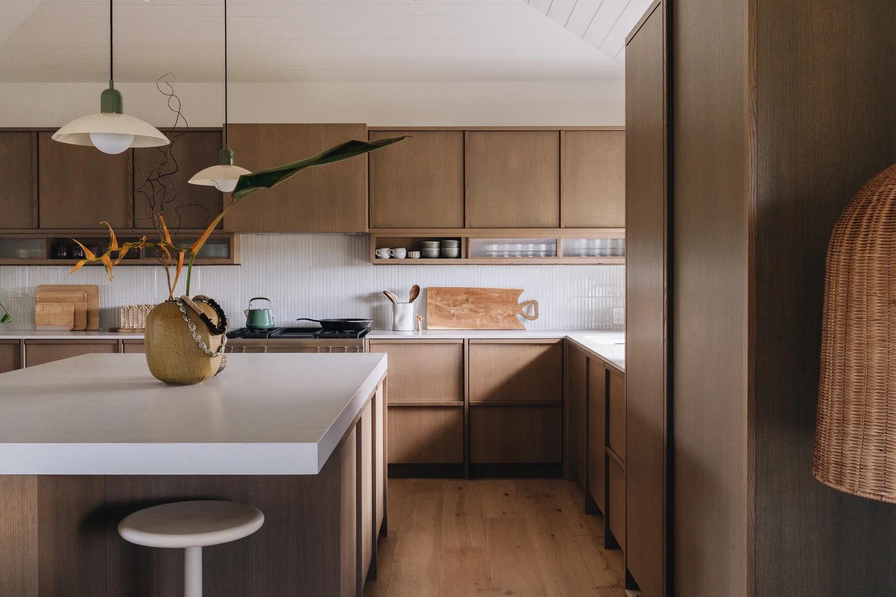 A modern kitchen with wooden cabinets, a central island, and pendant lights.