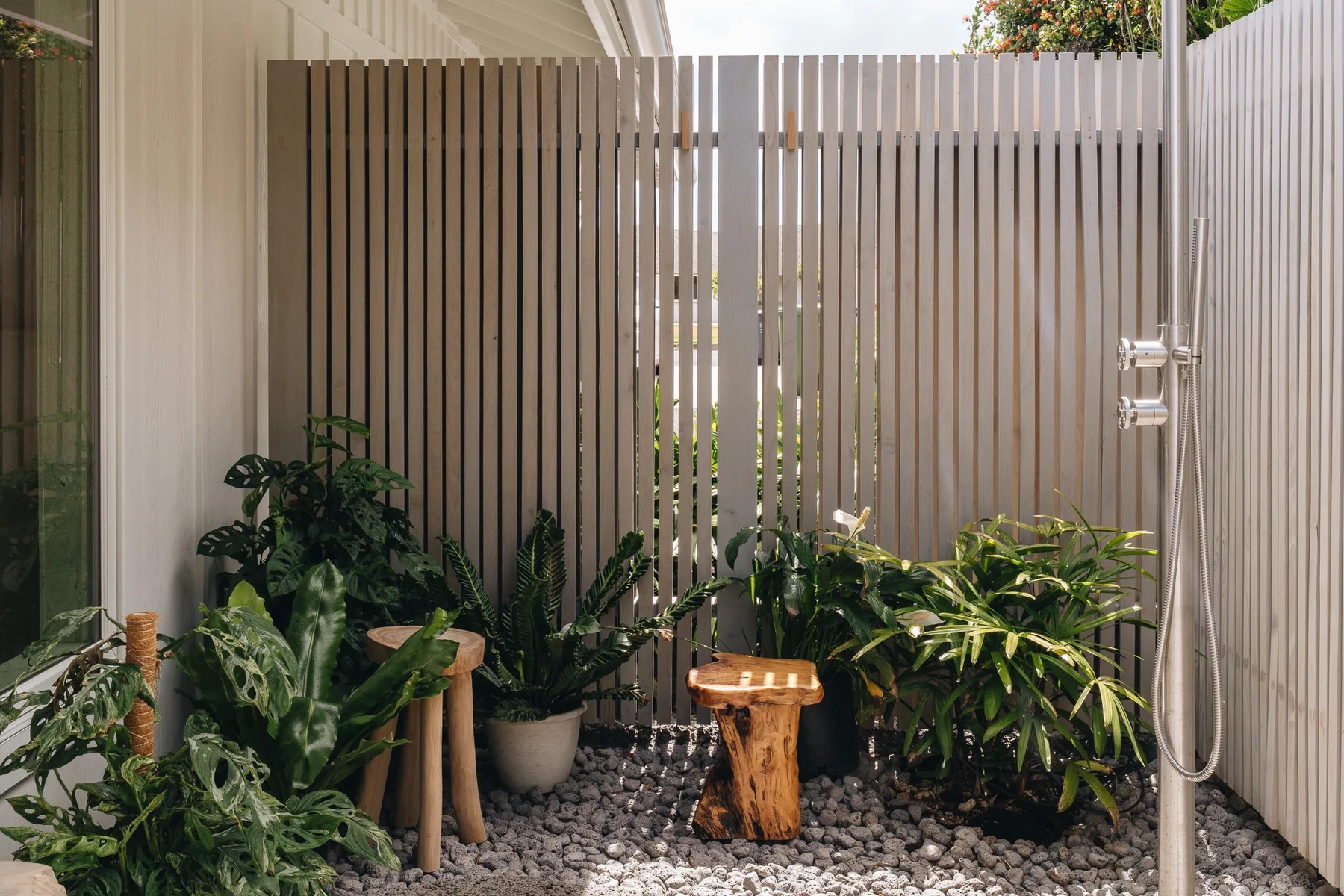A small outdoor patio with leafy plants and a gravel floor.