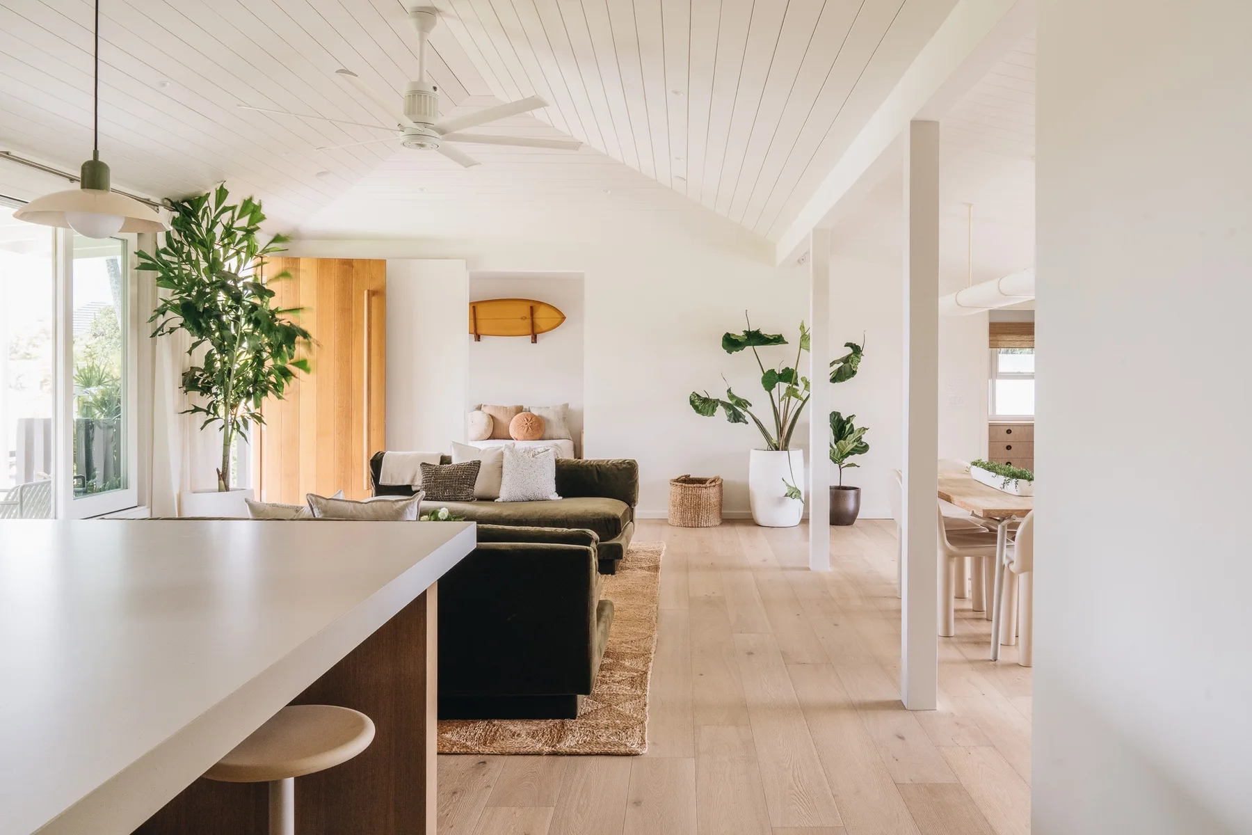 A bright living room with a dining counter and plants.