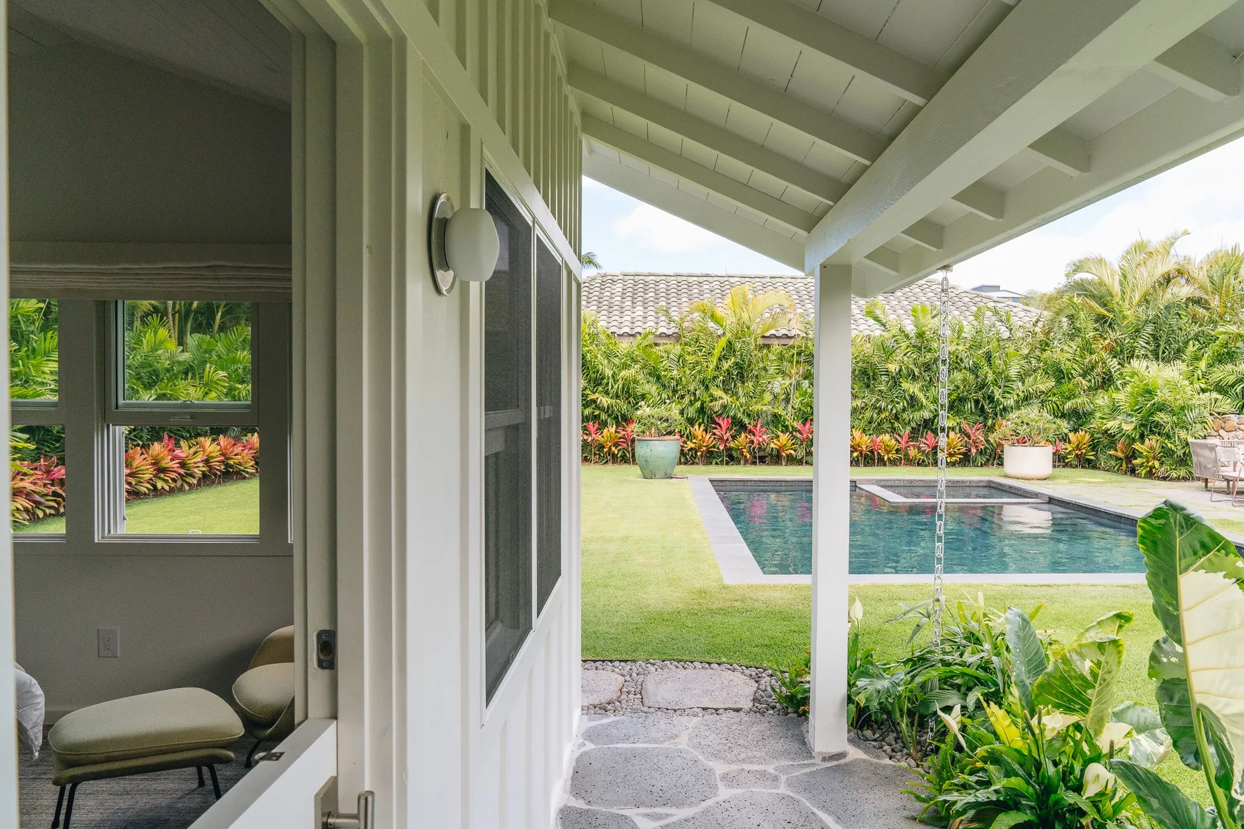 A covered patio opens onto a garden and swimming pool.