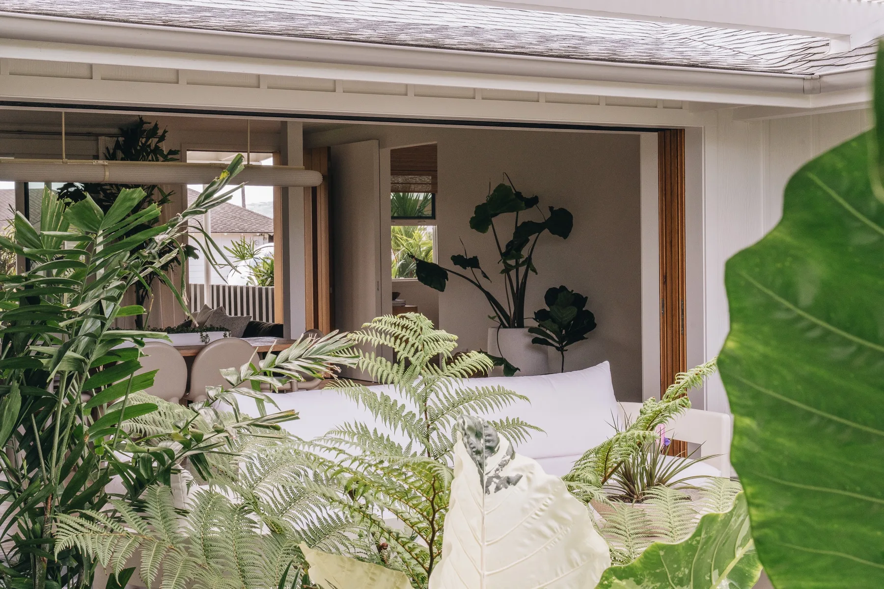 A bright indoor seating area opens onto a leafy patio through wide glass doors.