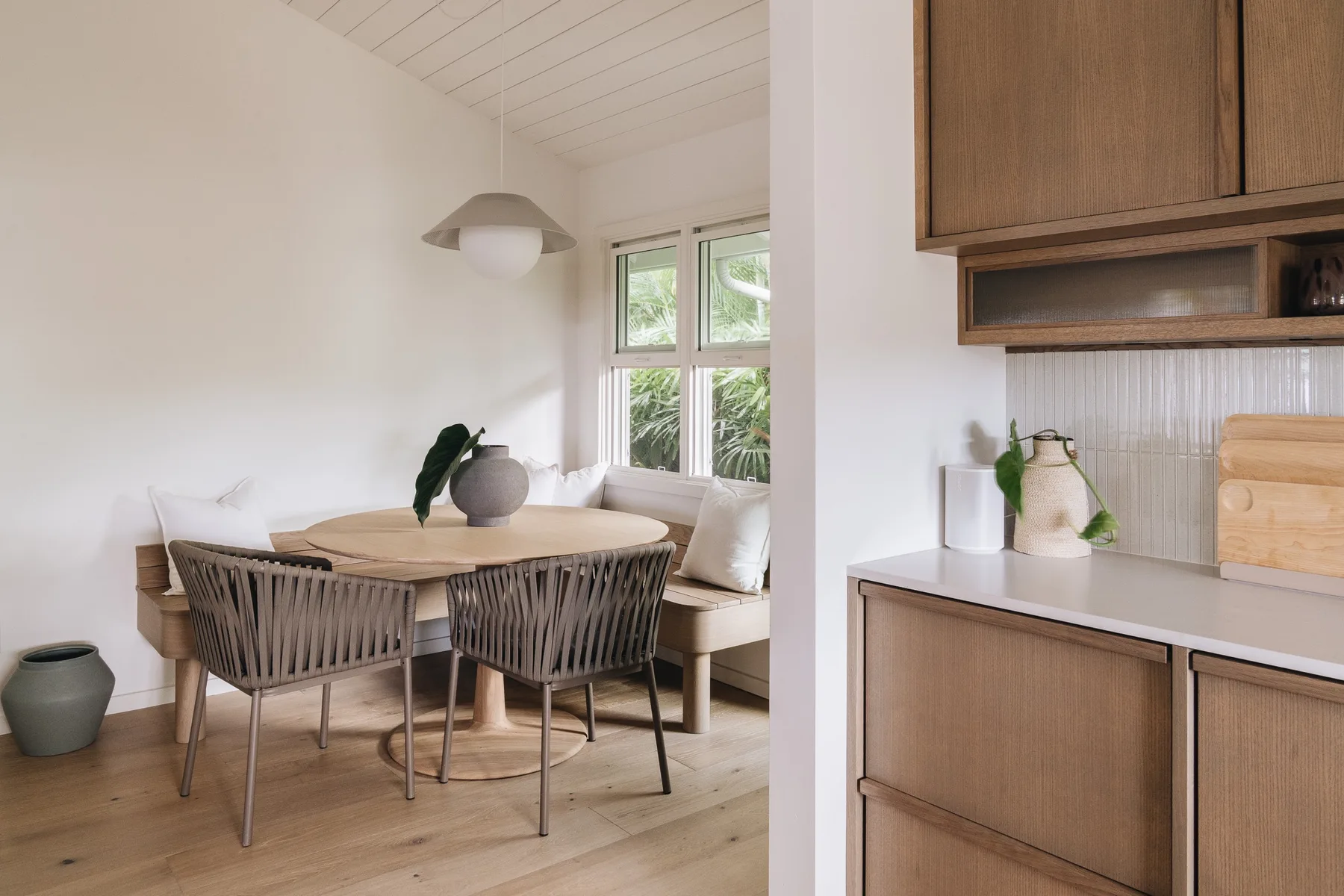 A dining area with a round table and seating sits beside a kitchen counter.